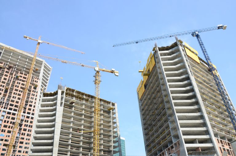 Construction site. High rise multi storey buildings under construction. Tower cranes near buildings