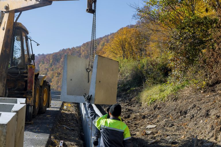 Concrete drain reconstruction workers installing precast square U-shape water channel construction